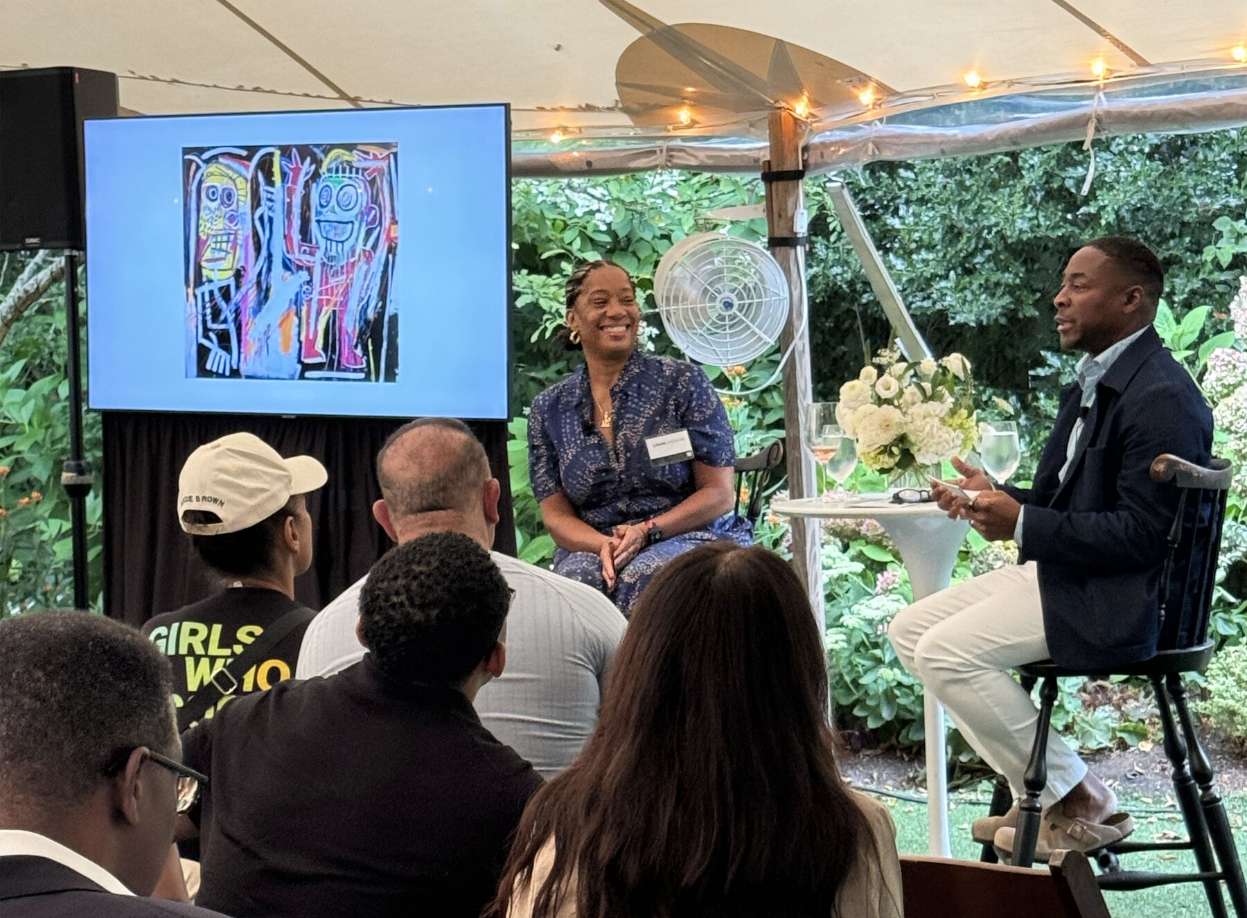 Lisane Basquiat in conversation with Franklin Sirmans at the TD Bank Empowered Futures event on Martha's Vineyard, Basquiat artwork on the screen behind them.