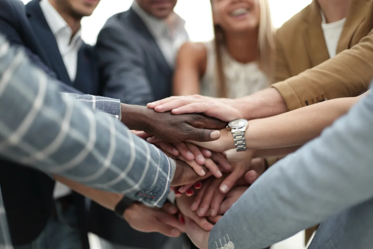 A diverse group of colleagues with hands stacked together in unity.