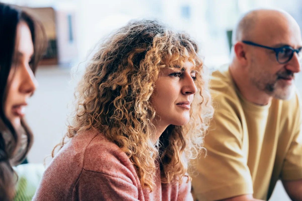 Three people listening intently in a group session.